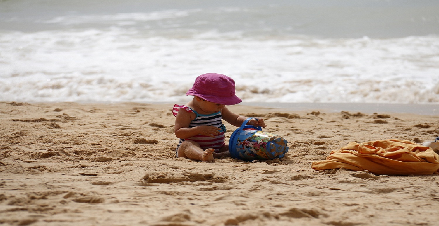 baby playing with a bucket on the beach